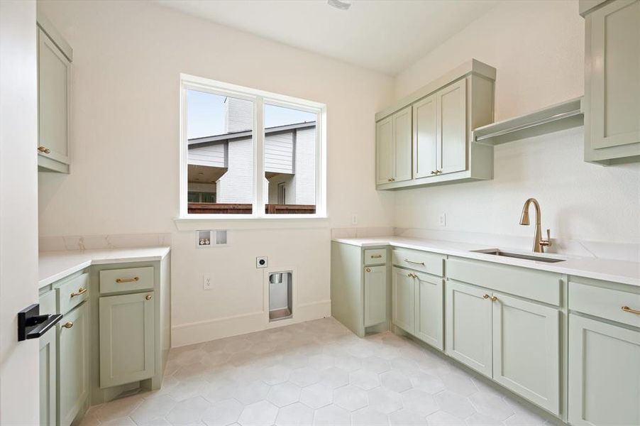 Laundry area featuring sink, electric dryer hookup, cabinets, light tile patterned floors, and washer hookup