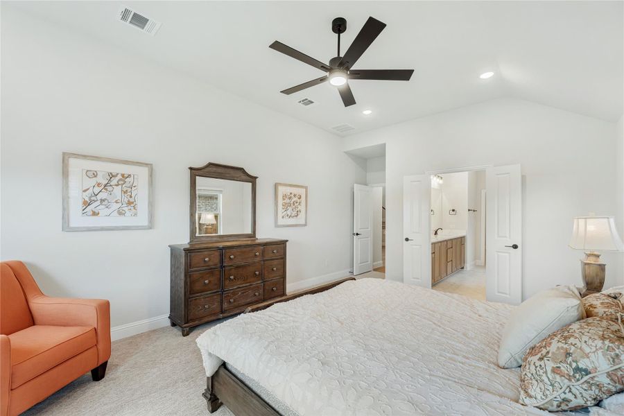 Bedroom with ceiling fan, wood dresser, and open door to ensuite bathroom