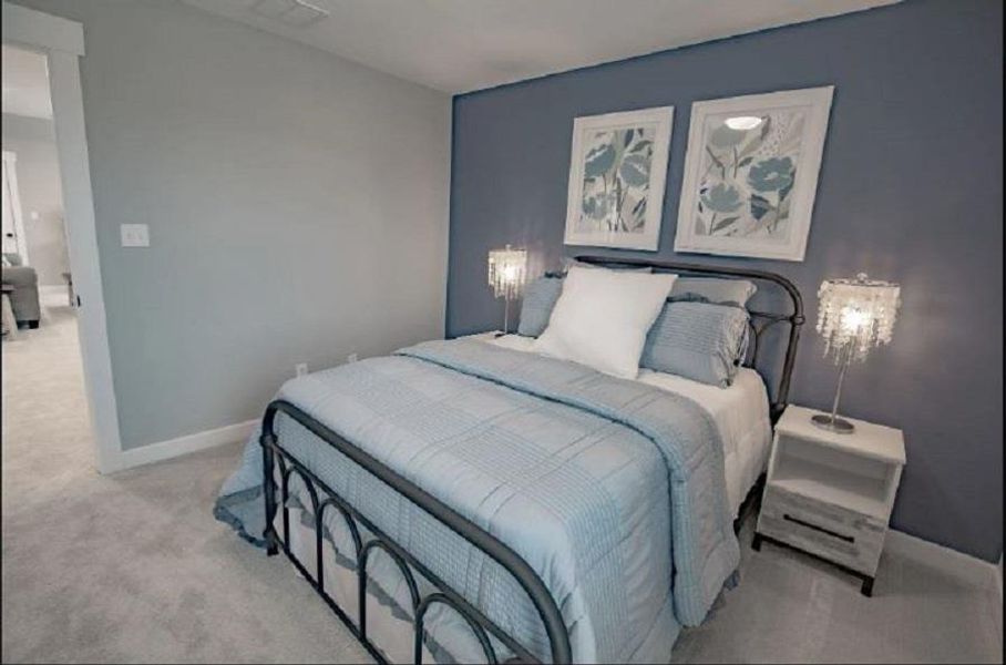 Bedroom featuring soft grey carpeting, a blue accent wall, and white trim