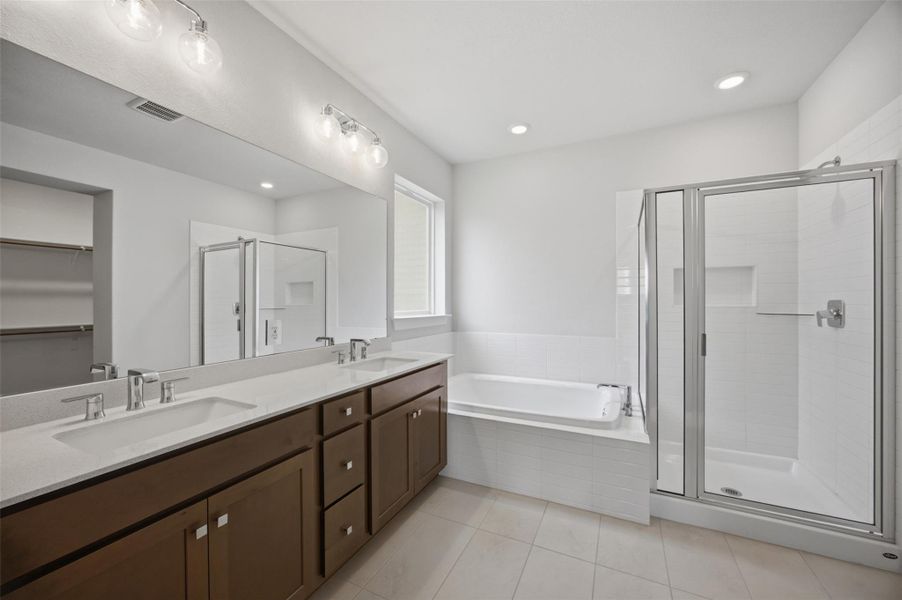 A well-appointed primary bathroom featuring dual vanities, a separate soaking tub, and a spacious walk-in shower.