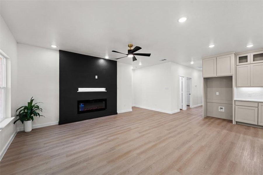 Spacious open-concept living area featuring an accent wall with a built-in electric fireplace and display ledge Spacious open-concept living area featuring an accent wall with a built-in electric fireplace and display ledge