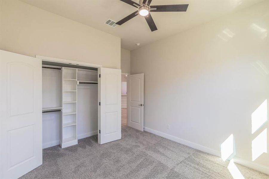 Unfurnished bedroom with ceiling fan, a closet, and light carpet