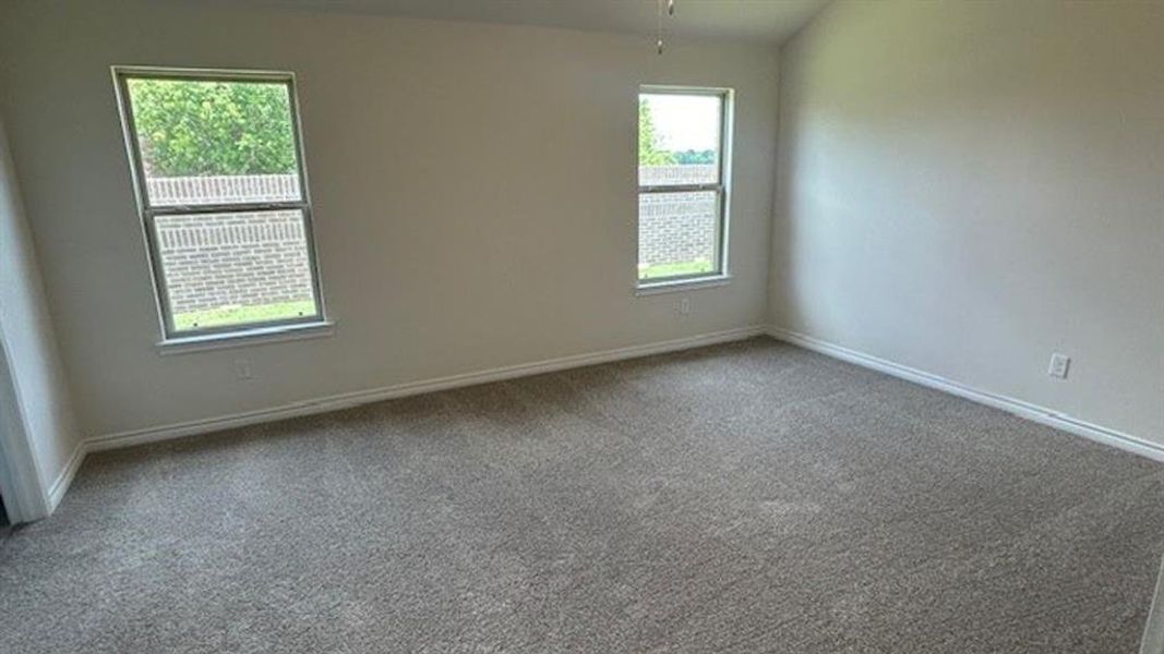 Spacious room featuring carpet flooring, two windows, and neutral wall paint