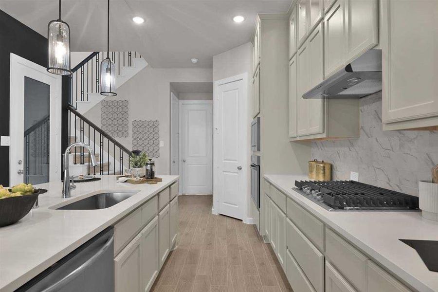 Gas cooktop, quartz counters, and abundant cabinet storage. (Original Builder Staged Photo 2024)