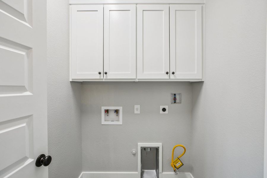 Washroom with hookup for a gas dryer, washer hookup, hookup for an electric dryer, and cabinet space