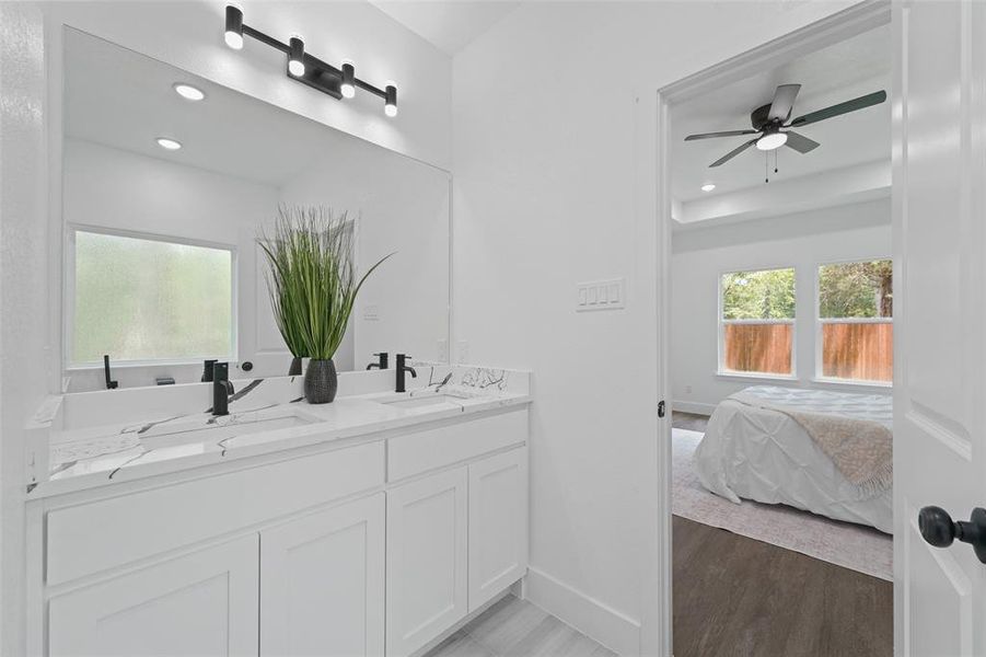 Bathroom vanity featuring a dual sink with matte black fixtures, a single large mirror, white cabinetry, and a window with frosted glass Bathroom vanity featuring a dual sink with matte black fixtures, a single large mirror, white cabinetry, and a window with frosted glass