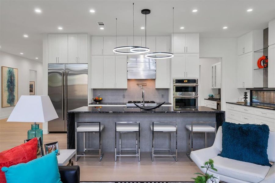 Kitchen with dark stone counters, white cabinets, stainless steel appliances, and a large island