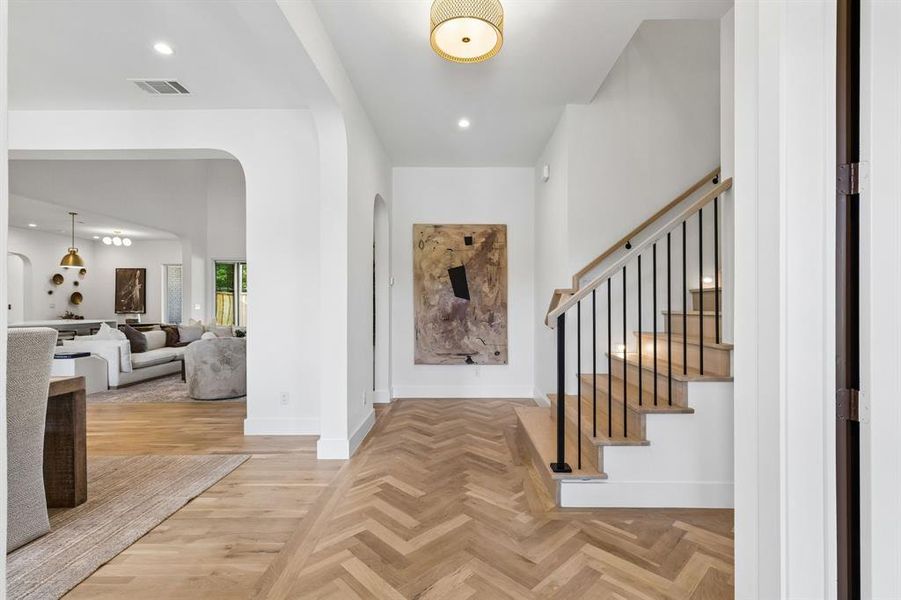 Foyer entrance with parquet flooring, recessed lighting, and arched walkways