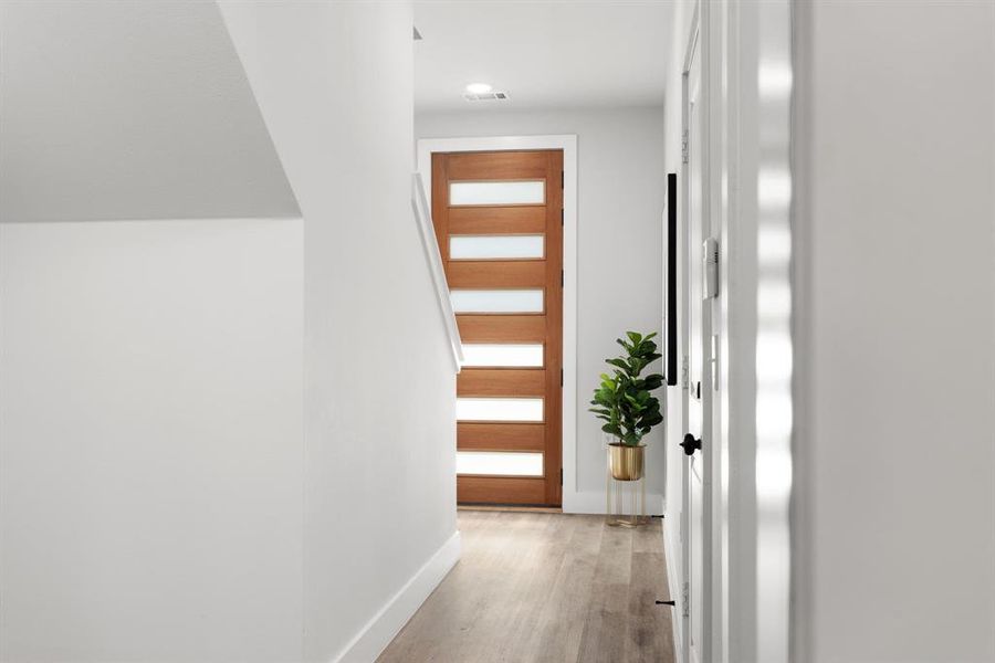 Hall featuring visible vents, light wood-style flooring, and baseboards