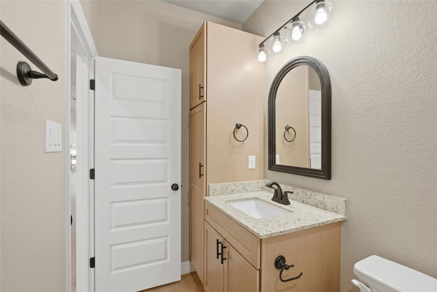 Half bathroom featuring vanity and a textured wall