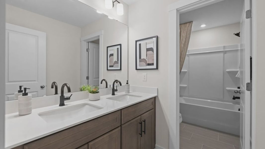Secondary bathroom with dual-sink vanity and large soak-in bathtub, in the Jordan Design by DRB Homes in York, SC