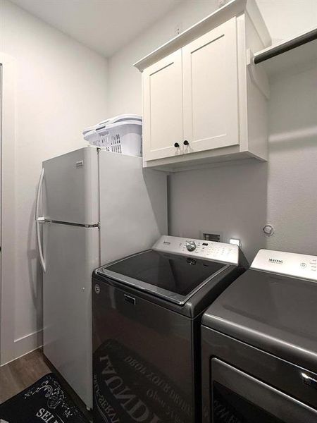 Washroom featuring wood finished floors, cabinet space, and washer and dryer Washroom featuring wood finished floors, cabinet space, and washer and dryer