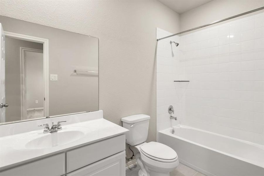 The secondary bath features tile flooring, white cabinetry and light countertops and a shower/tub combo. Perfect for accommodating any visiting family and friends.