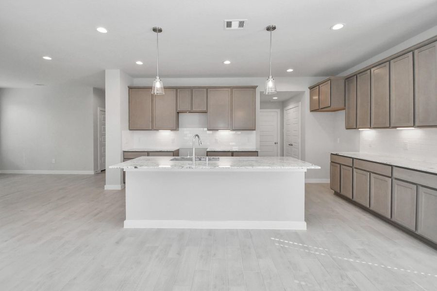 The kitchen is a culinary haven, featuring granite countertops, a tile backsplash, stainless steel appliances, 42” upper cabinets, and undercabinet lighting. Sample photo of completed home with similar floor plan. Actual colors and selections may vary.