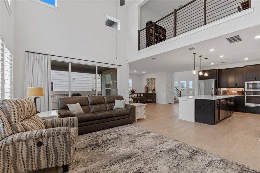 Living area with light wood-style flooring, a high ceiling, and recessed lighting