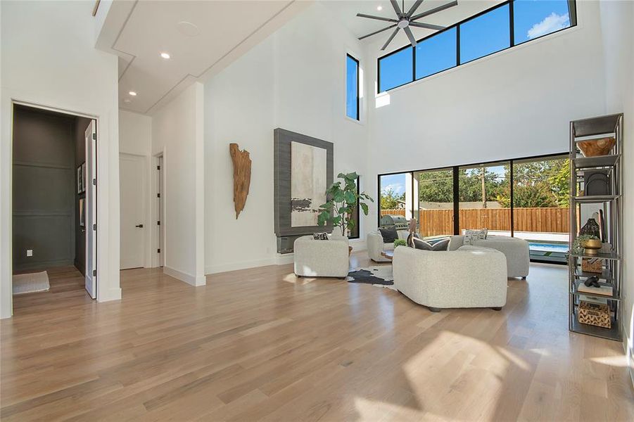 Living room featuring recessed lighting, light wood-type flooring, and a towering ceiling