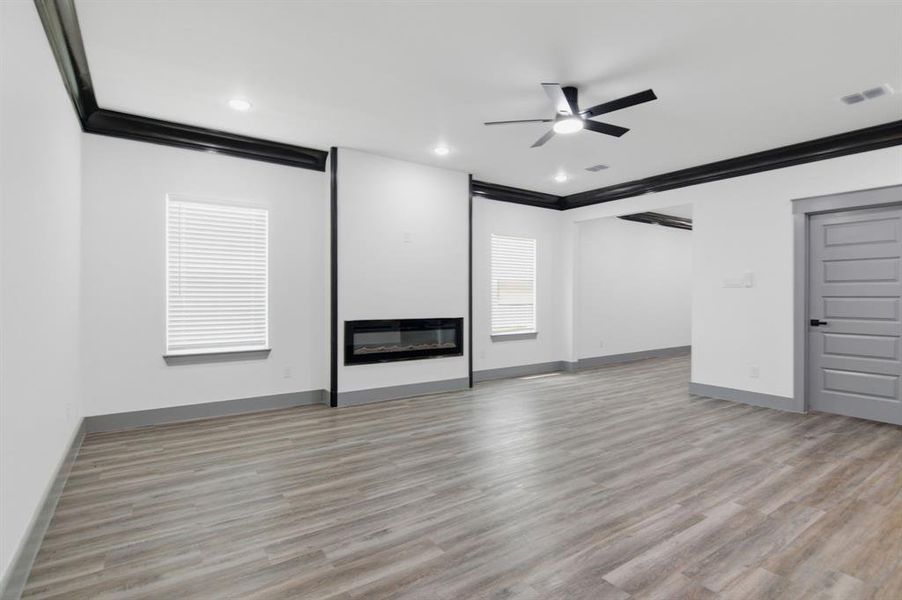Spacious interior featuring wood-finish flooring, a contemporary linear electric fireplace, recessed lighting, and a ceiling fan