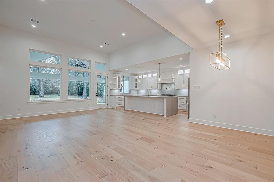 This spacious, open-concept living area features large windows offering abundant natural light, hardwood floors. creating a bright and airy atmosphere perfect for entertaining.