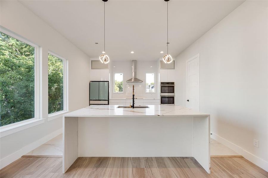Kitchen with white cabinetry, modern cabinets, light wood-type flooring, and recessed lighting Kitchen with white cabinetry, modern cabinets, light wood-type flooring, and recessed lighting