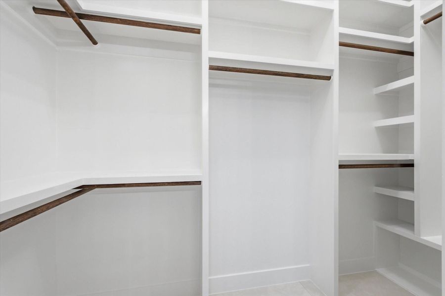 Wardrobe Perfection. Never run out of space with this expertly designed, fully custom walk-in closet featuring floor-to-ceiling built-in shelving, double hanging rods, and sleek wood accents.