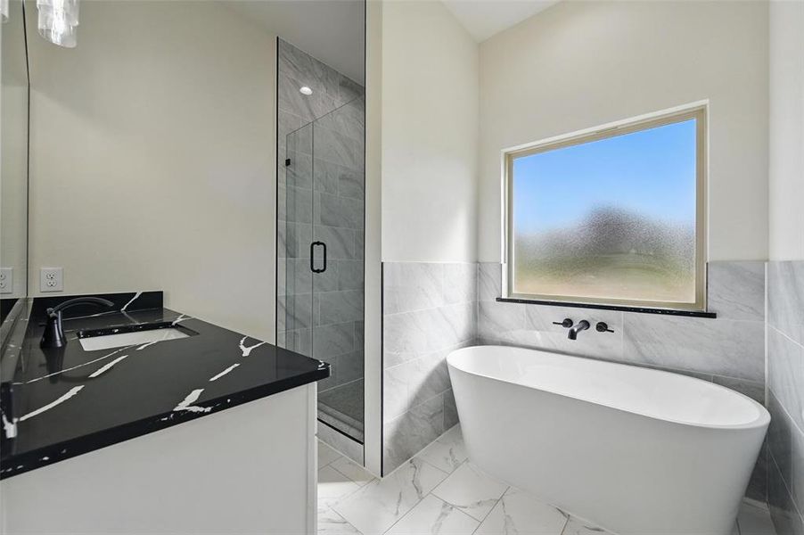 Full bath featuring a shower stall, marble look tiles, a freestanding tub, vanity, and tile walls Full bath featuring a shower stall, marble look tiles, a freestanding tub, vanity, and tile walls
