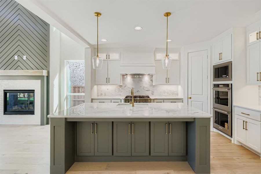 Kitchen featuring recessed lighting, white cabinets, light stone countertops, hanging light fixtures, and a glass covered fireplace Kitchen featuring recessed lighting, white cabinets, light stone countertops, hanging light fixtures, and a glass covered fireplace