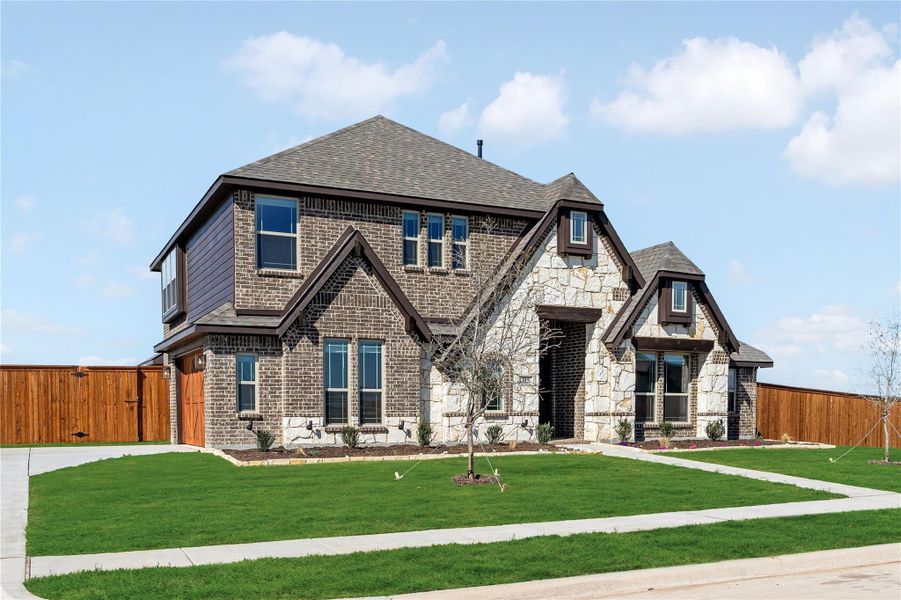 Two-story brick and stone home with dark trim, green lawn, and wood privacy fence Two-story brick and stone home with dark trim, green lawn, and wood privacy fence