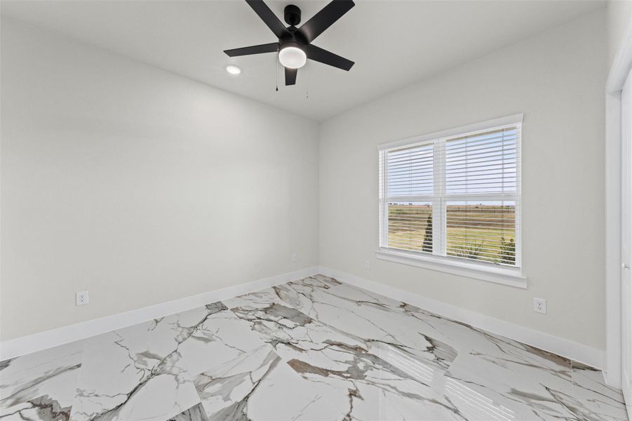 Polished stone tile flooring pairs with neutral walls and a large, sunlit window.