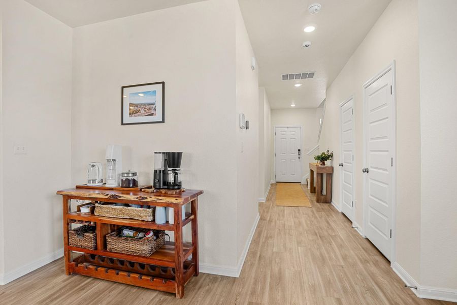 A well-lit entry hall with light wood flooring leads to a welcoming front door, offering a clear path through the home's initial approach.