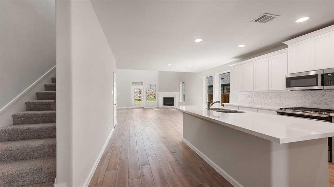 Kitchen with sink, wood-type flooring, decorative backsplash, and stove