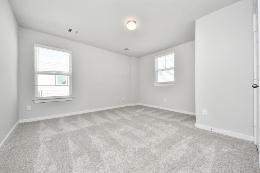 Secondary bedroom features plush carpeting, large windows that let in plenty of natural light, bright paint, and spacious closets. Sample photo of completed home with similar floor plan. Actual colors and selections may vary.
