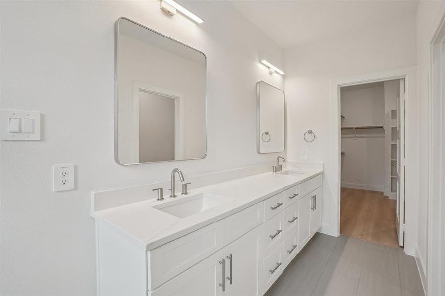 Bathroom with double vanity and a walk in closet