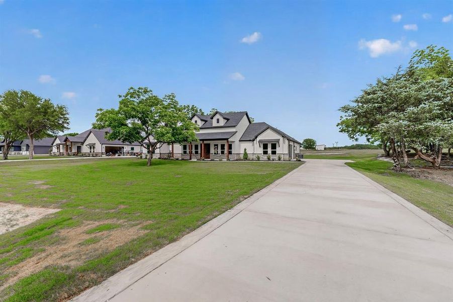 Expansive concrete driveway approaching a single-story residence with a dark roof and light-toned siding