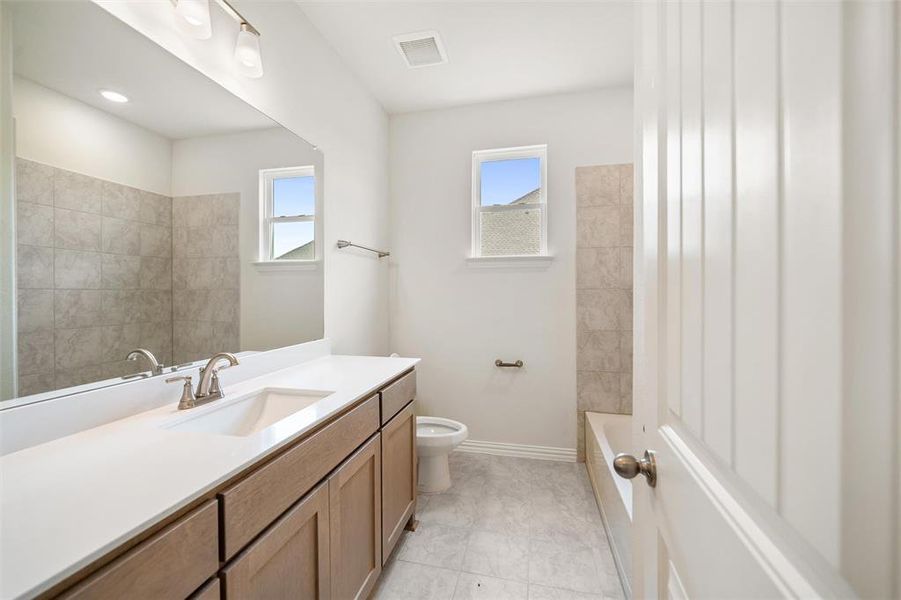 Bathroom with vanity, plenty of natural light,  shower combination, and light tile patterned floors