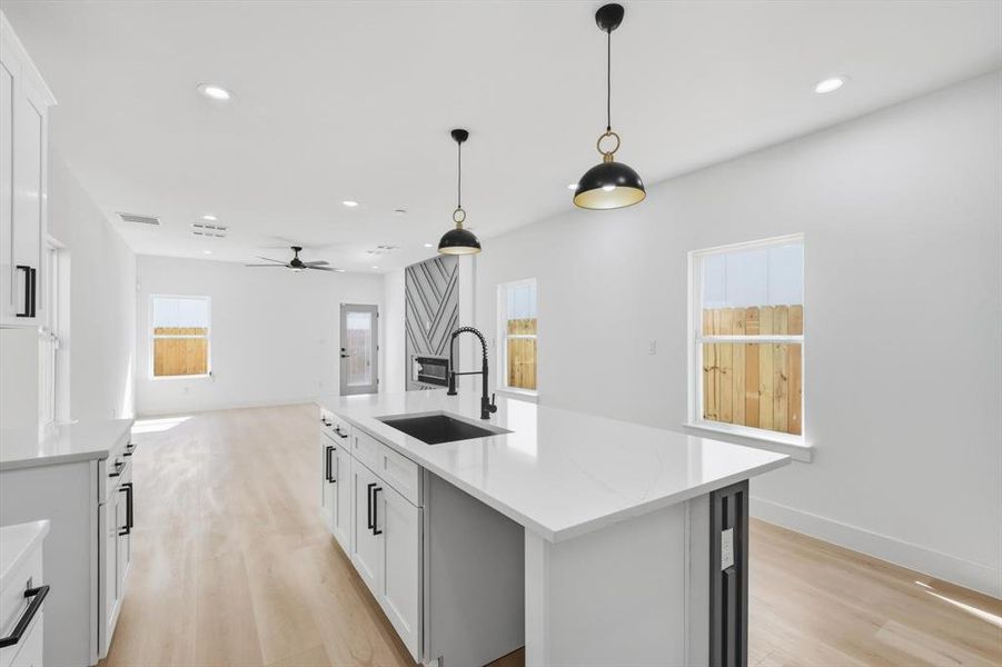 Kitchen featuring white cabinets, light wood-style flooring, a kitchen island with sink, and open floor plan