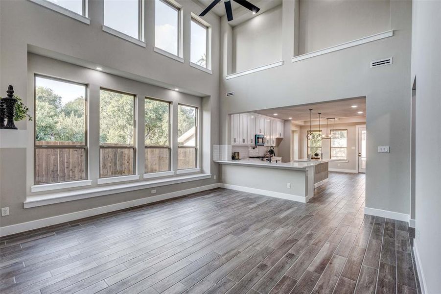 Gorgeous living  area with dark wood-look tiled flooring, a ceiling fan, and a high ceiling