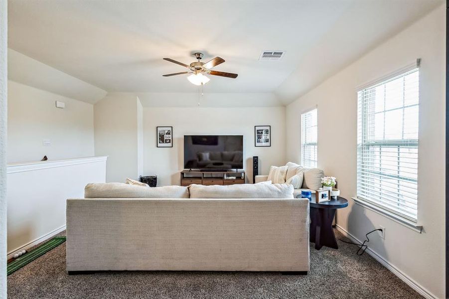 Living room with vaulted ceiling, ceiling fan, and dark carpet