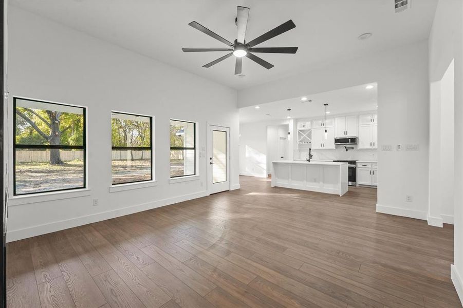 Unfurnished living room with ceiling fan and dark wood-type flooring