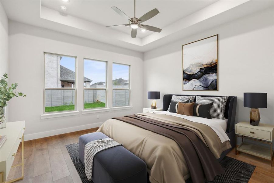 Bedroom with ceiling fan, light hardwood / wood-style floors, and a tray ceiling