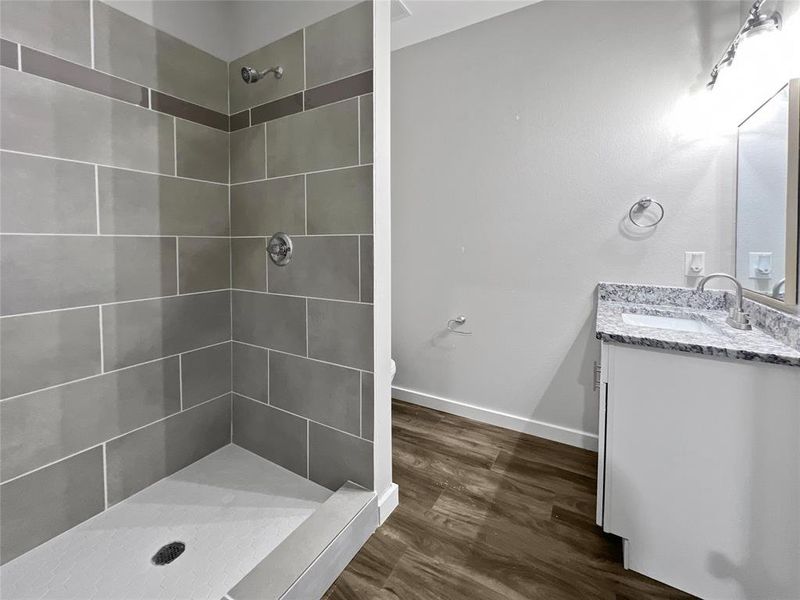 Bathroom with vanity, a tile shower, toilet, and hardwood / wood-style flooring