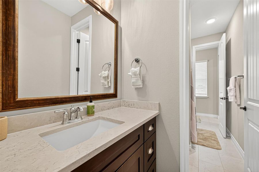 Elegant shared bath featuring dual sinks, granite countertops, and framed mirrors. Elegant shared bath featuring dual sinks, granite countertops, and framed mirrors.
