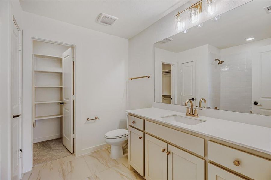 Full bath featuring a spacious closet, vanity, light marble finish flooring, recessed lighting, and a shower