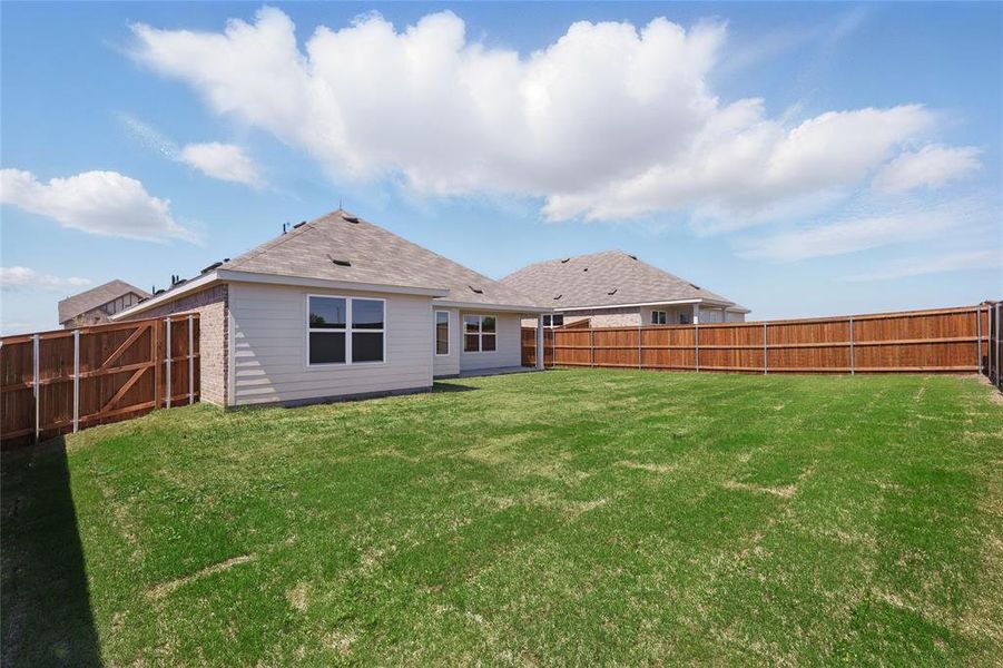 Back of house featuring brick siding, a fenced backyard, and a lawn Back of house featuring brick siding, a fenced backyard, and a lawn