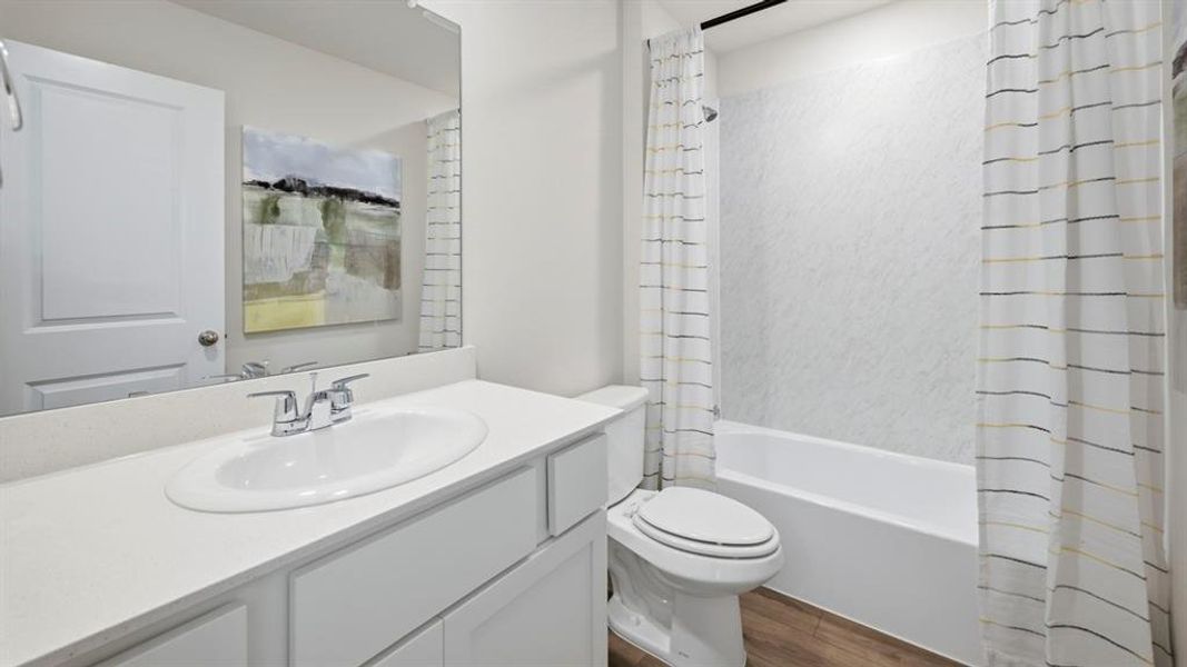 Bathroom featuring vanity, shower / bath combination with curtain, and dark wood-style flooring Bathroom featuring vanity, shower / bath combination with curtain, and dark wood-style flooring