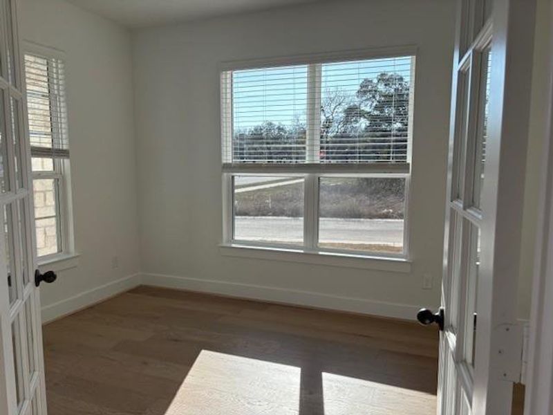 Empty room with french doors, wood finished floors, and baseboards