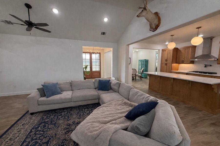 Living room featuring vaulted ceiling, recessed lighting, ceiling fan, and wood finished floors Living room featuring vaulted ceiling, recessed lighting, ceiling fan, and wood finished floors