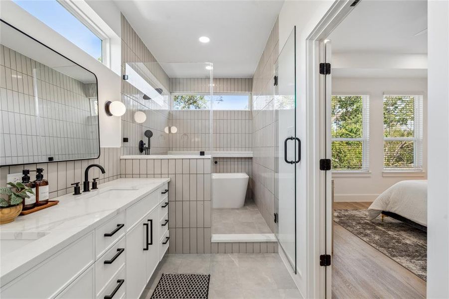 Luxurious en-suite bathroom seamlessly connected to the primary bedroom, featuring a dual vanity, frameless glass shower, soaking tub, and contemporary finishes with a warm, natural light-filled ambiance.