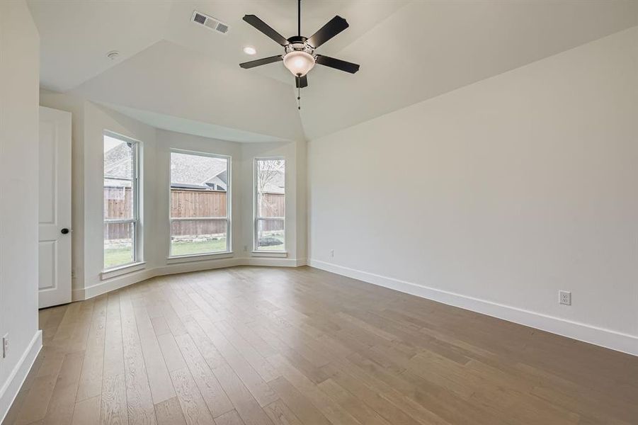 Spare room featuring light wood finished floors, ceiling fan, and vaulted ceiling