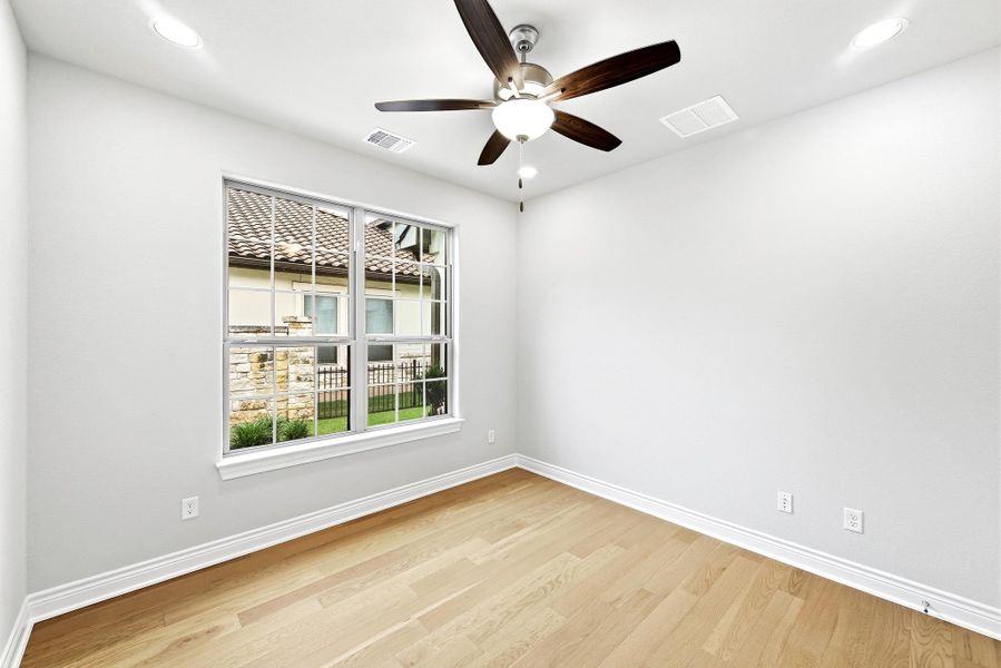 Bright room featuring light wood-finish flooring, white baseboards, and a contemporary ceiling fan with a light kit