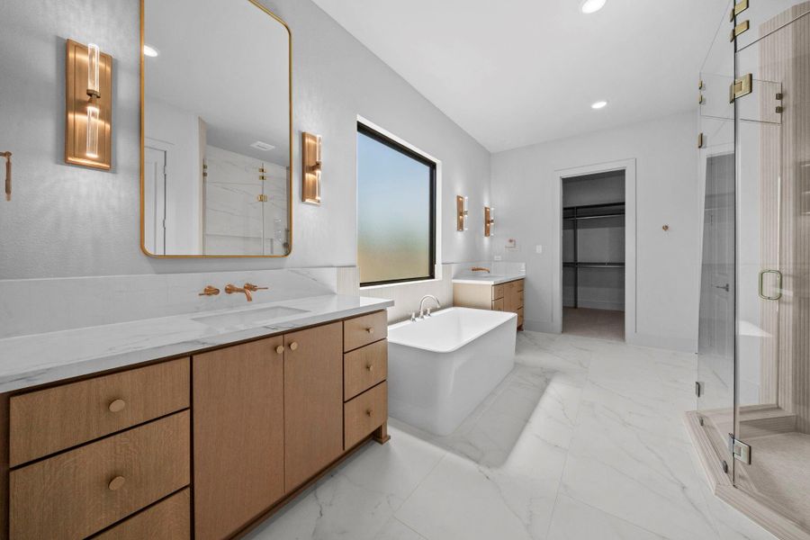 Luxurious primary bathroom featuring dual vanities, elegant finishes, and a spacious design.